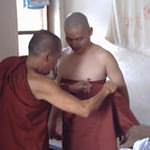 Helping the future monk to wear his robe